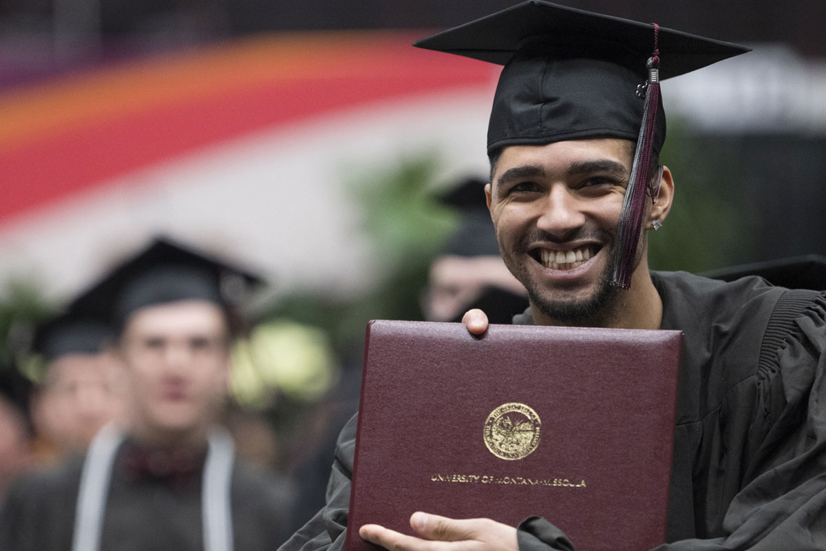 A UM student holds his diploma at Commencement.