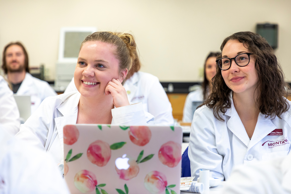 Two UM students sit in a STEM class with white jackets.